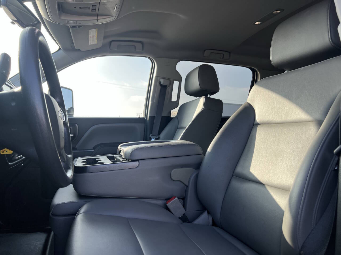 Interior view of a Chevrolet Silverado truck cabin with front seats, center console, and steering wheel visible. Visible text includes overhead console and dashboard details.