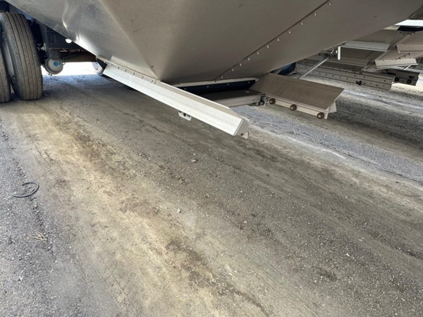 Underbelly of a 2024 Timpte Super Hopper trailer showing side auger/step components and underside structure.