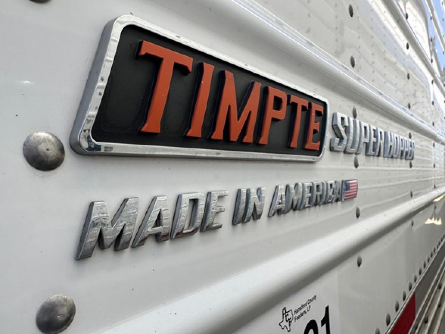 Trailer side showing TIMPTE SUPER HOPPERS branding with MADE IN AMERICA text and riveted aluminum surface.
