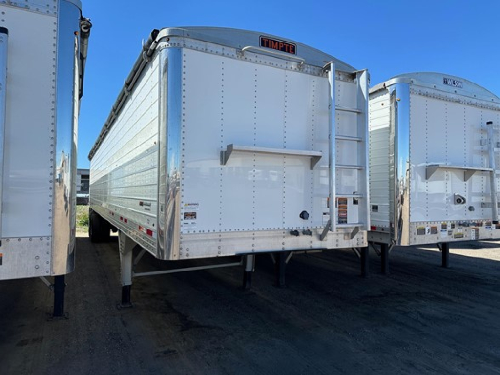 Timpte Super Hopper trailer rear view showing aluminum body and rear access door with TimPte logo, dual support legs, and reflective markers.