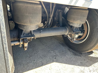Trailer axle and suspension underside with air tanks and driveline components visible; no legible brand or serial text.