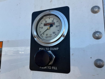 Timpte gauge panel showing pull to dump and push to fill with a round dial gauge reading around 0-100 and a blue knob. Text: PULL TO DUMP, PUSH TO FILL.