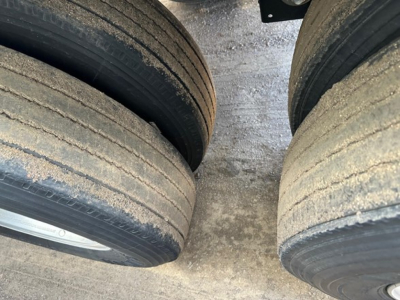 Trailer axle showing dual tires with dirt and wear visible on treads and sidewalls.