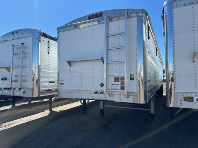 Timpte Super Hopper trailer rear view showing fold-down ladder and hitch, metal paneling, and landing gear.