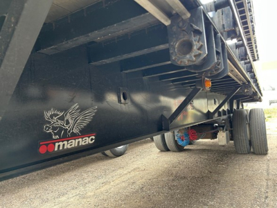 Manac extendable steel flatbed trailer side view showing Manac logo and underside structure.