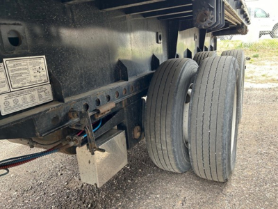 Extendable steel flatbed trailer undercarriage with dual rear wheels and mounting hardware; visible labels and frame components