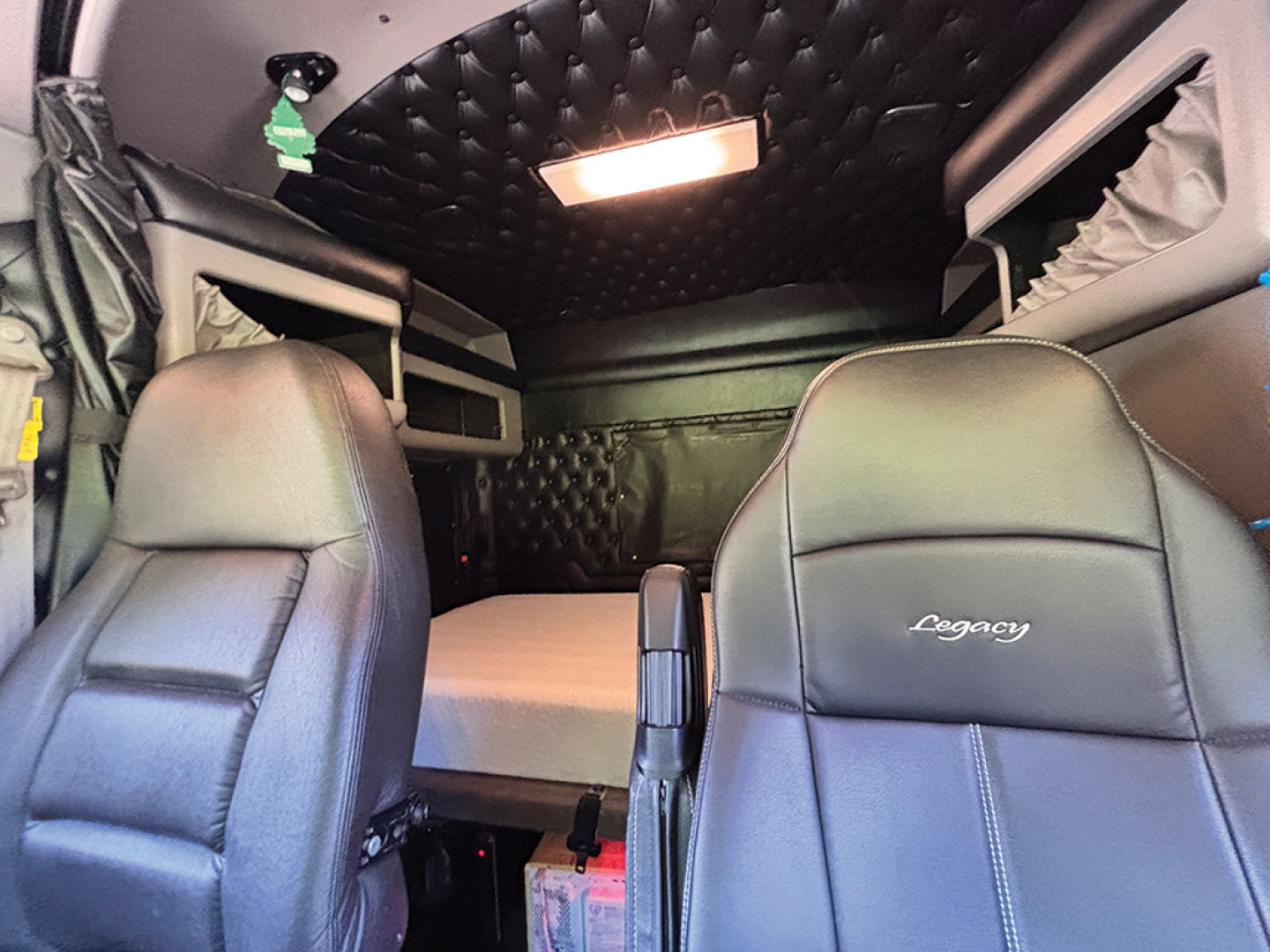 Kenworth W-900 AeroCab interior showing front seats and sleeper area with quilted ceiling panel and overhead light.