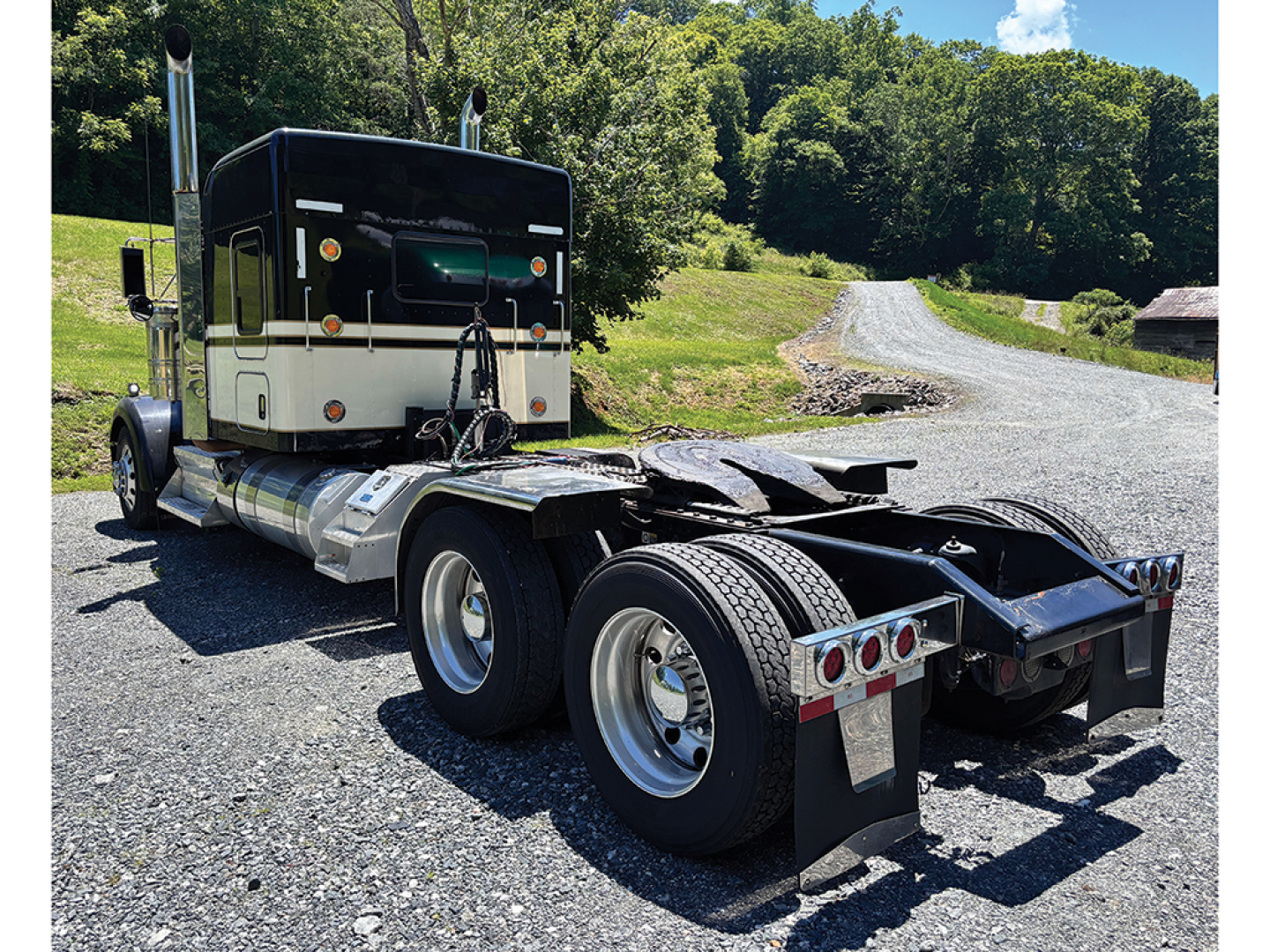Kenworth W-900 AeroCab tractor rear view showing sixth wheel and bumper, with dual rear axles and side tanks.