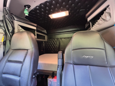 Kenworth W-900 AeroCab interior showing front seats and sleeper area with quilted ceiling panel and overhead light.