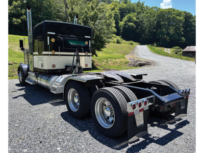 Kenworth W-900 AeroCab tractor rear view showing sixth wheel and bumper, with dual rear axles and side tanks.