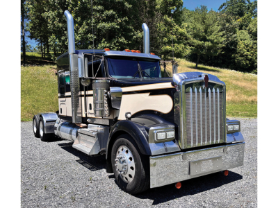 Kenworth W-900 AeroCab conventional sleeper truck in service view with chrome bumper and stacked exhaust stacks.