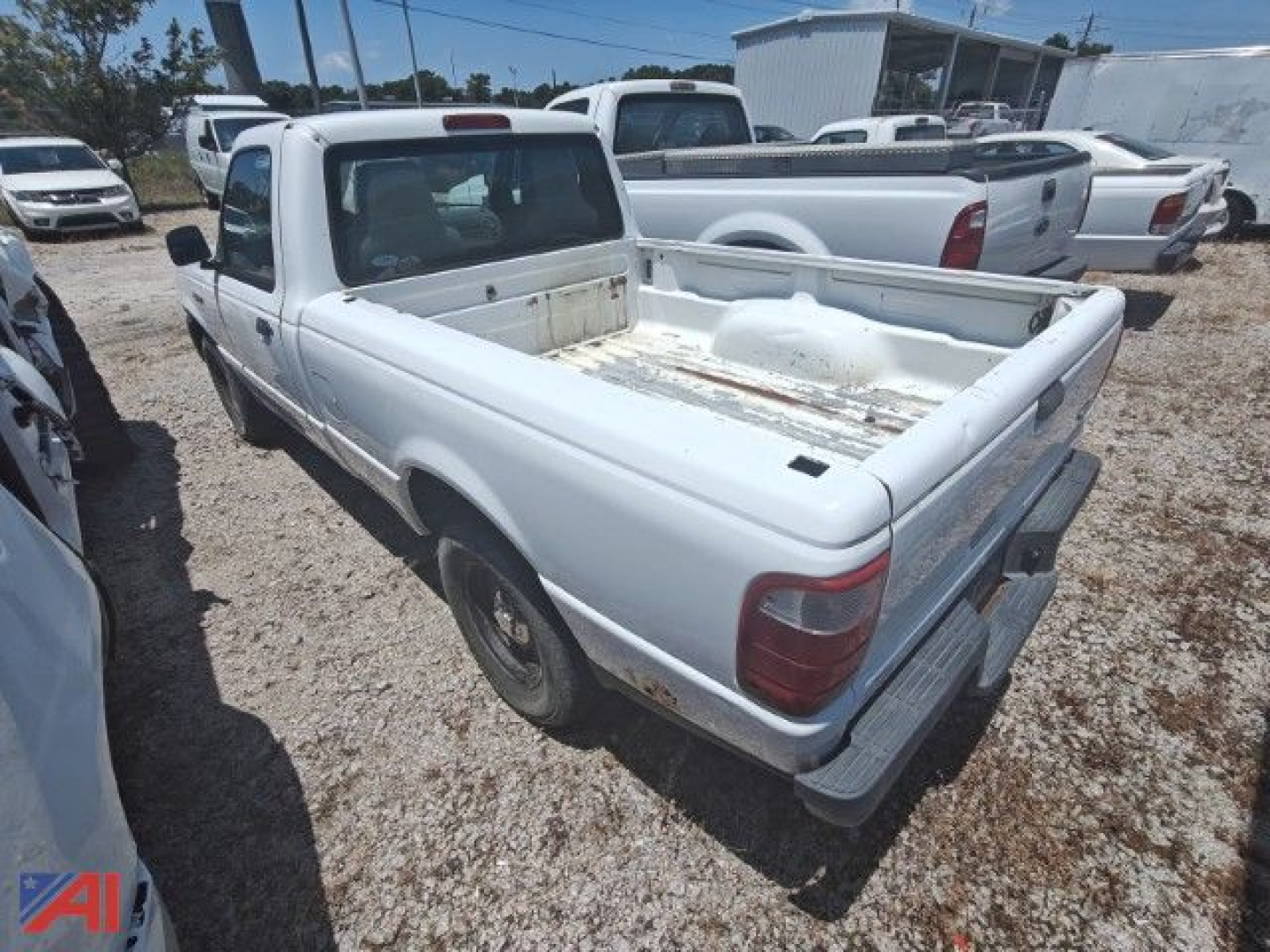 White 2005 Ford Ranger pickup truck with an empty bed, rear three-quarter view, in a used-truck lot.
