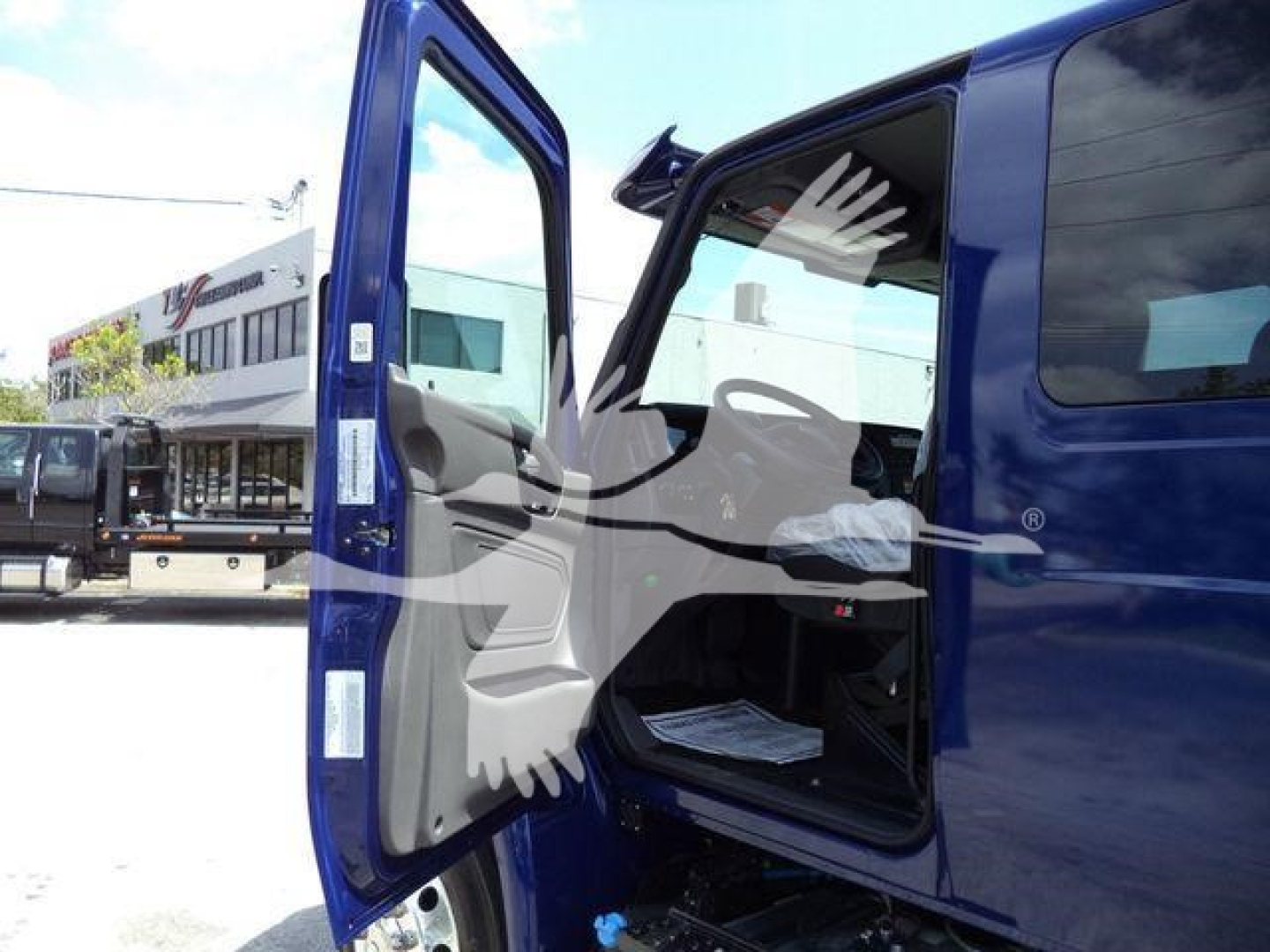 Truck cab door open showing interior seating and dashboard of a blue 2027 International MV rollback truck.