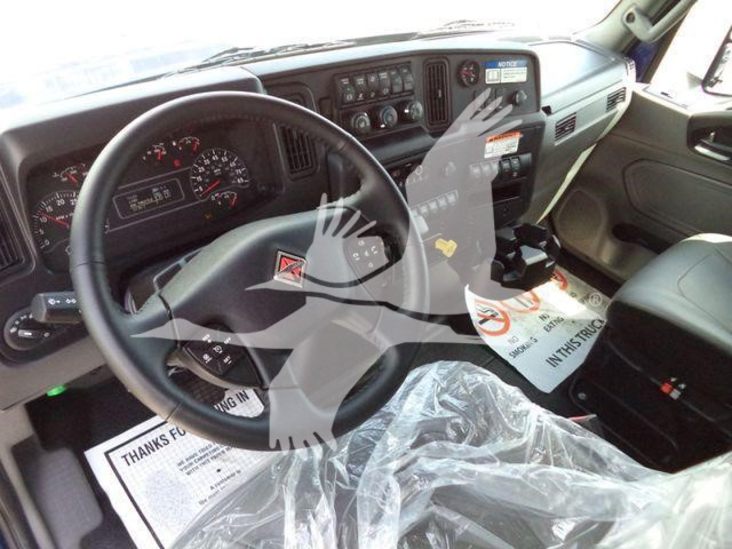 Cab interior of a 2027 International MV truck showing steering wheel, dashboard gauges, and driver's seat.