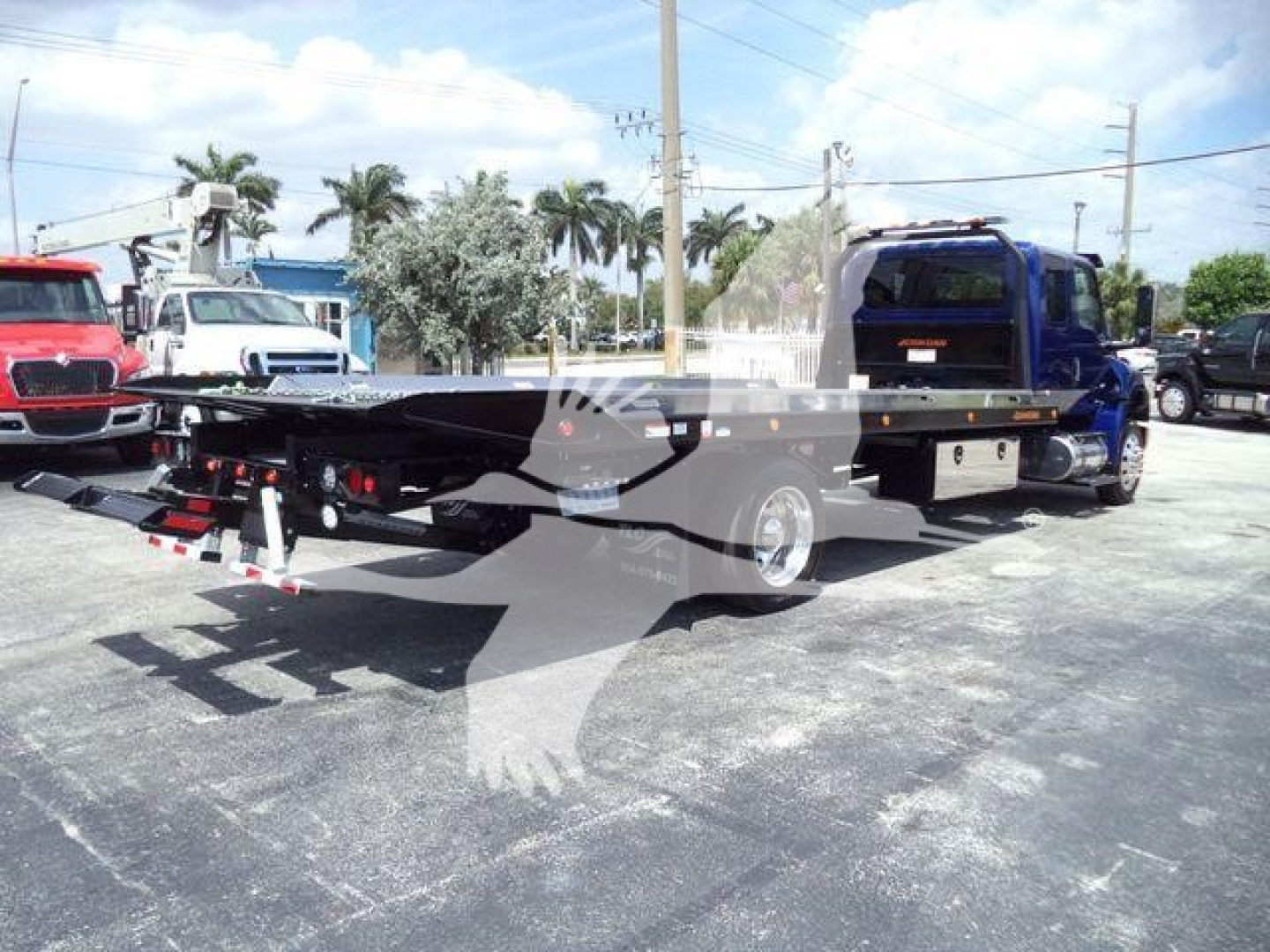 mv607excabblu International MV rollback truck on lot with flatbed towing equipment visible from rear-left perspective.