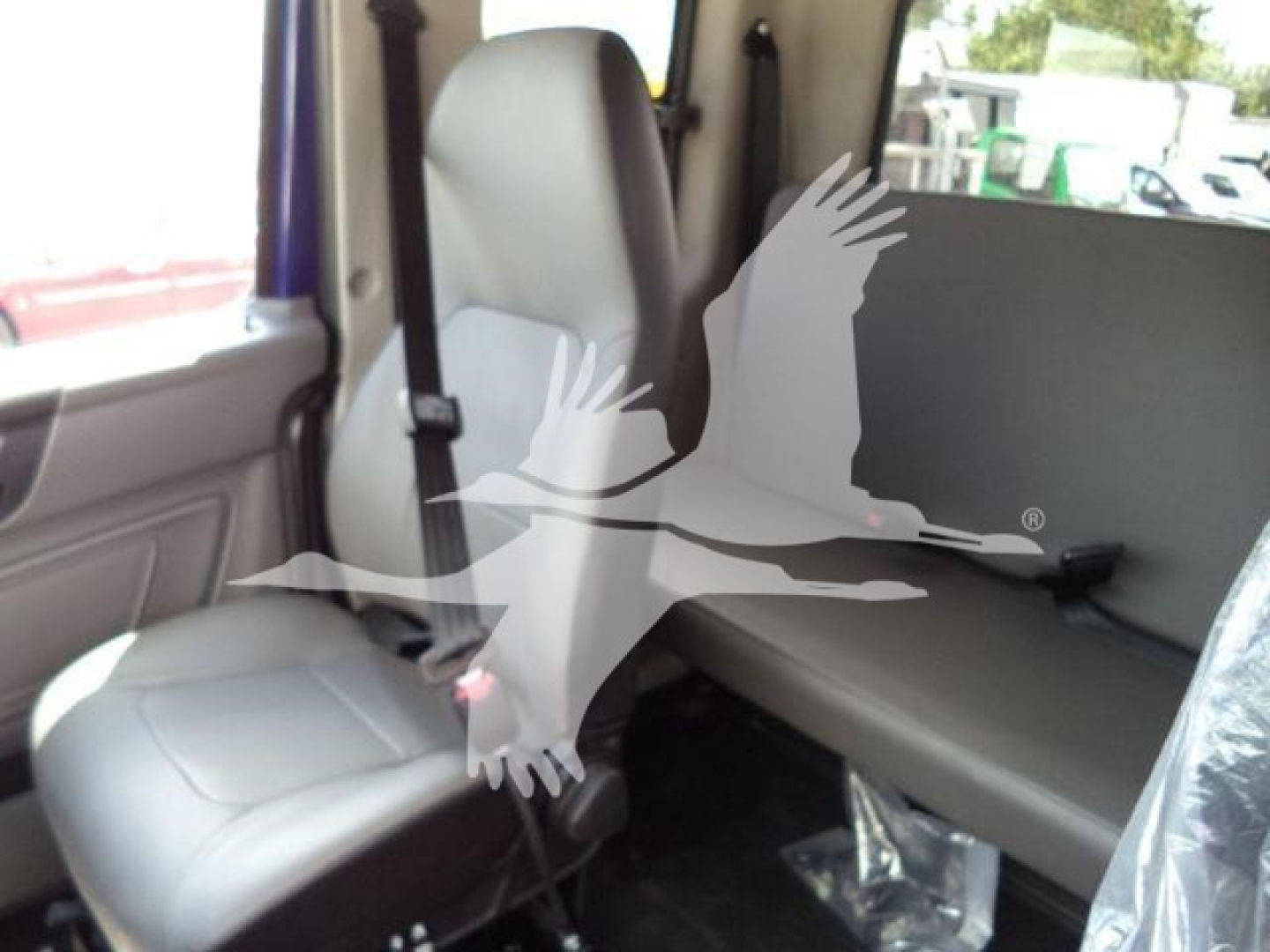 Interior of a new 2027 International MV rollback truck showing front passenger seat and rear bench seat with seat belts.