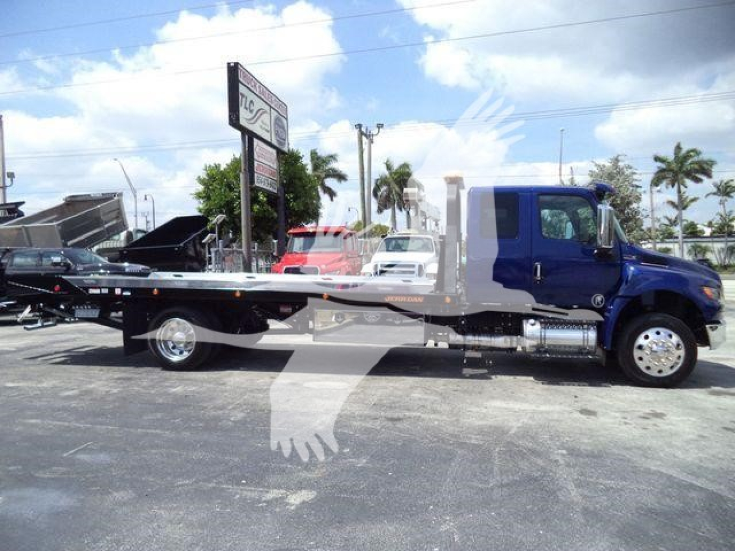 International MV tow truck flatbed showing blue cab and black flatbed with chrome wheel covers.