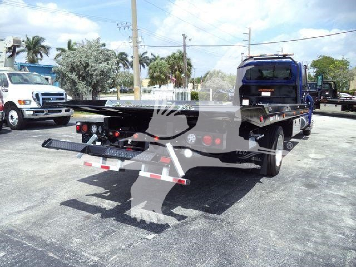 Truck bed on a rollback tow truck with rear ramps and hoses visible
