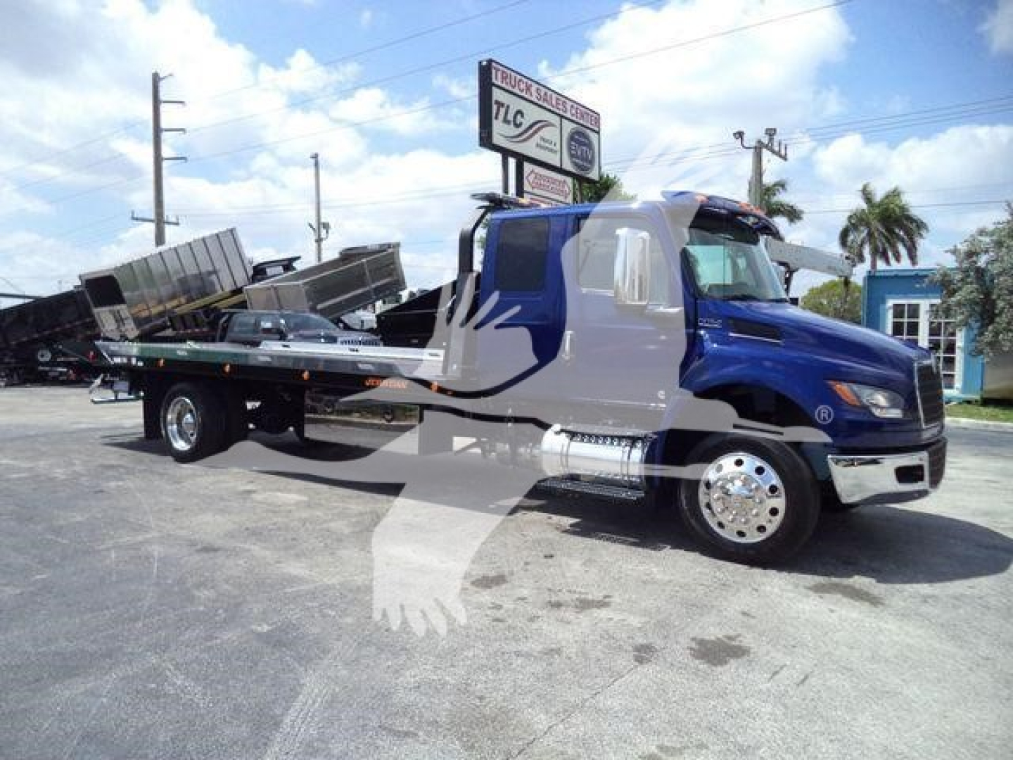 International MV rollback truck showing flatbed tow unit with blue cab and chrome accents.