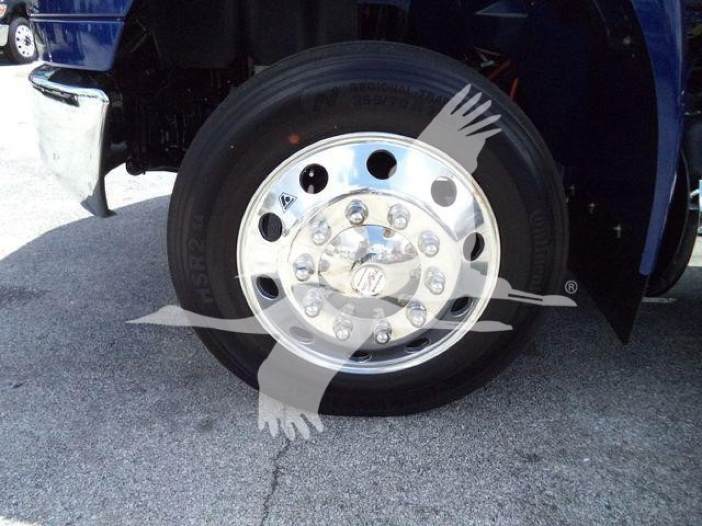 Wheel and tire of a new 2027 International MV truck showing polished chrome hub with lug nuts and center cap.