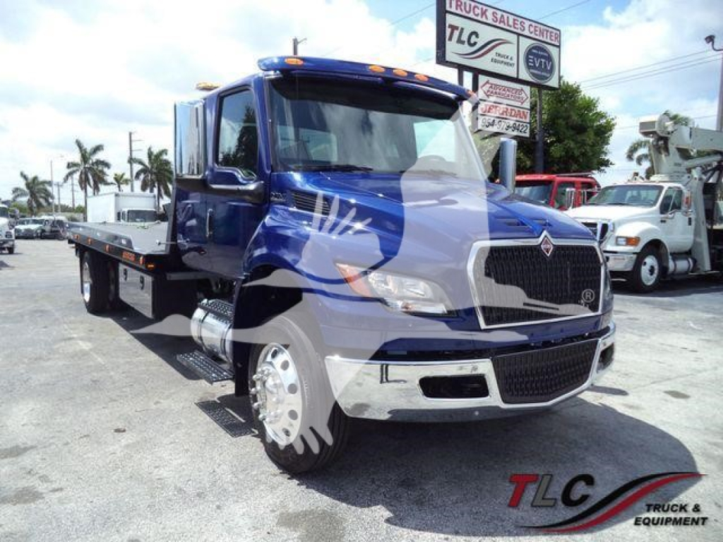Truck showing MV607EXCABBLU International MV rollback w/ blue cab and flatbed, front grille, large side mirrors.