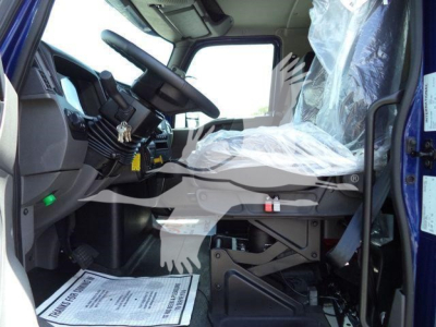 Interior of a new 2027 International MV rollback truck cab showing driver seat, steering wheel, and dashboard with plastic seat covers.