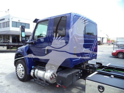 Truck cab side view showing blue International MV cab with chrome fuel tanks and side steps. Image includes rear chassis and empty truck bed.