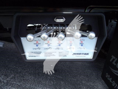 Truck hitch control panel with multiple toggle levers and Jerr-Dan branding, mounted on a black metal frame under the rear of a vehicle.