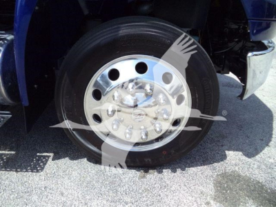 Wheel and tire assembly on a blue truck with polished steel hub and lug nuts visible.