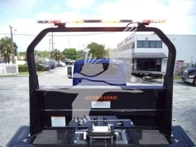Truck bed with rollover equipment and frame, black metal, orange Jordan logo, illuminated cab in background, highway scene.