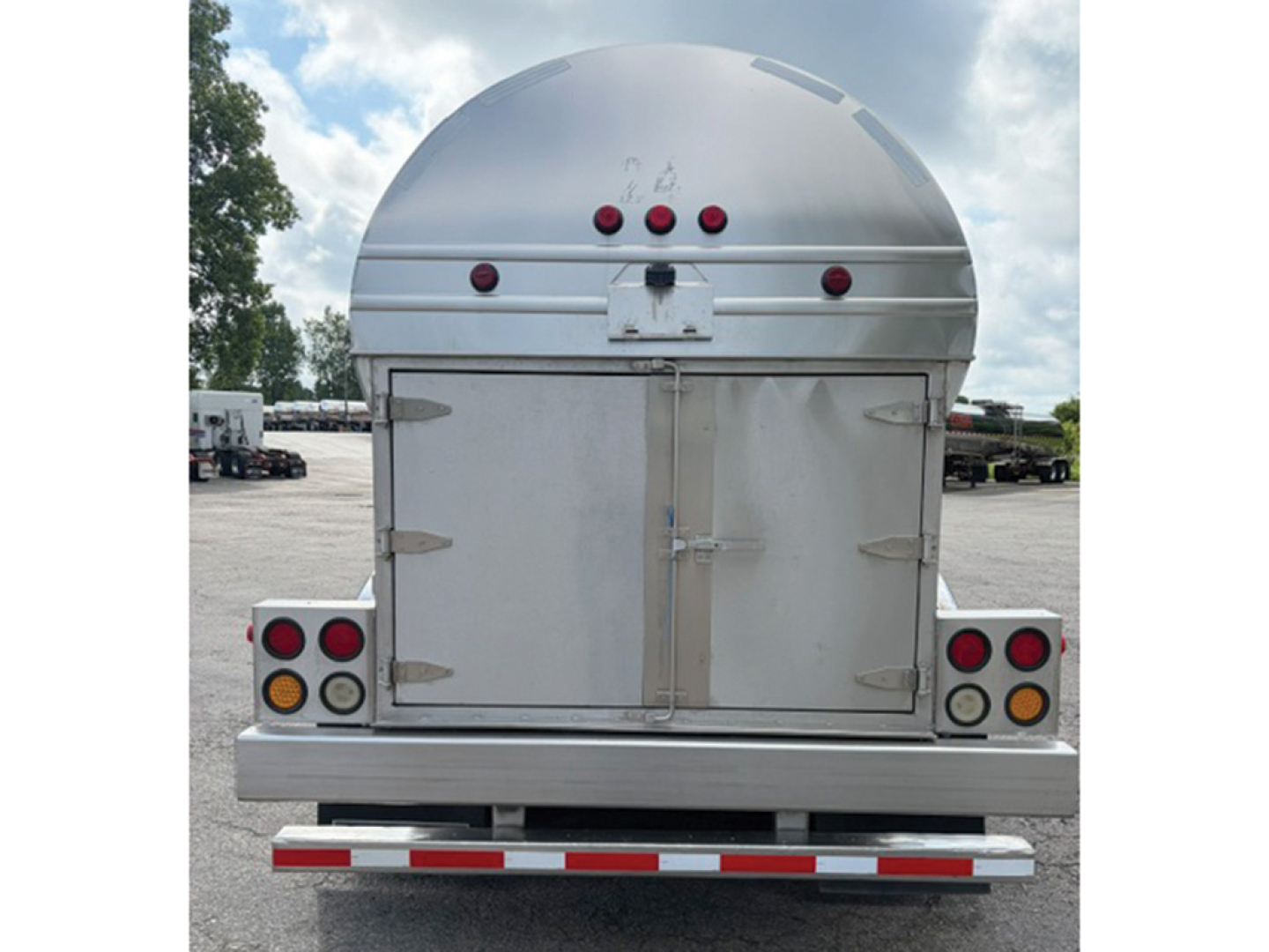 Rear view of a Brenner STPU62001ISS trailer showing dual rear doors, circular fuel tank above, and taillights with reflectors.