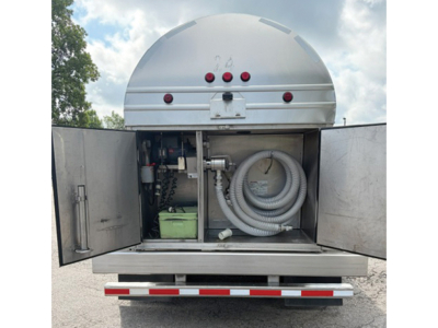 Tank trailer back with open compartments showing hoses and a green battery/box inside.