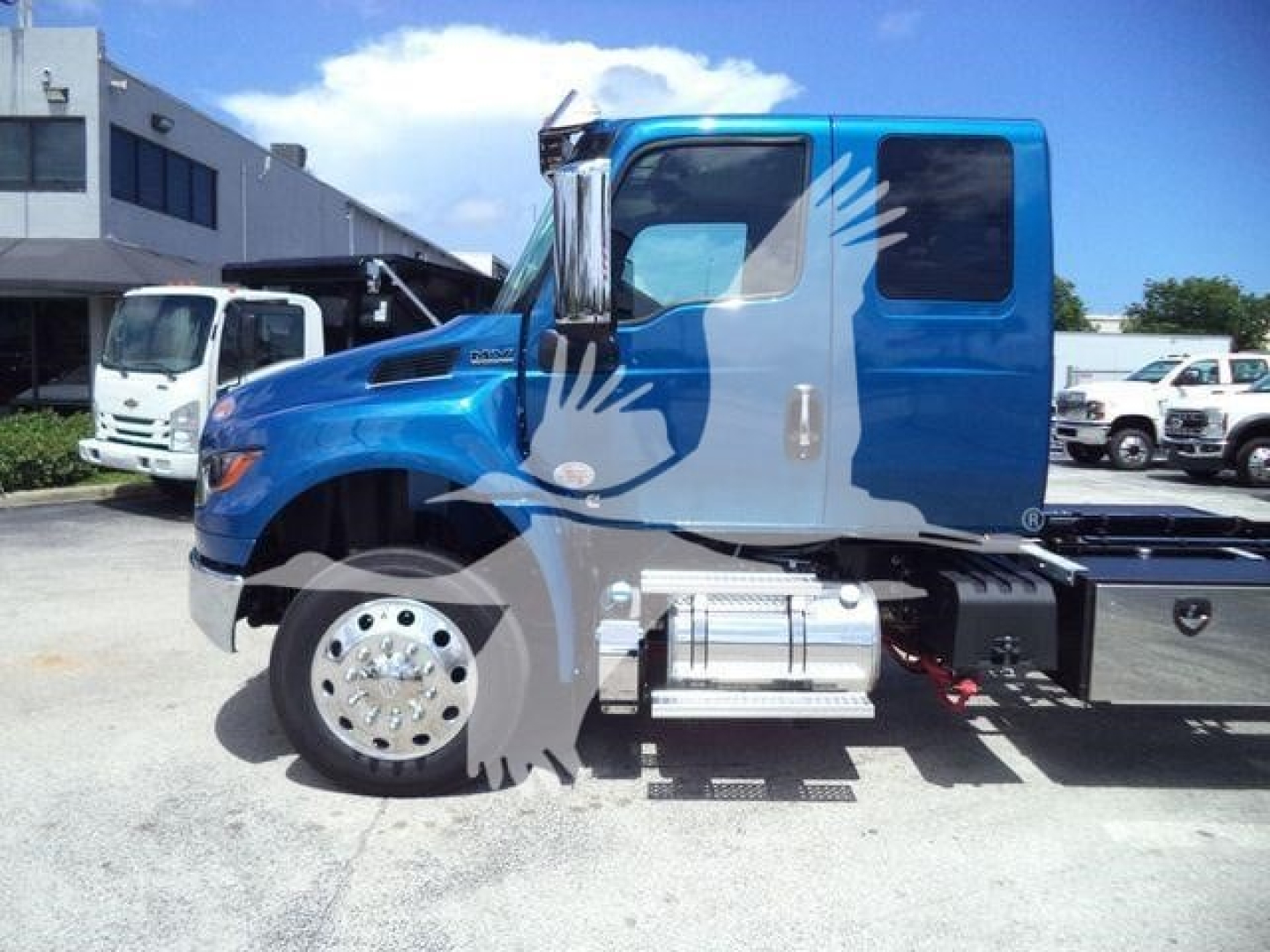 Blue International MV rollback truck in side view showing cab, fuel tanks, and chassis.