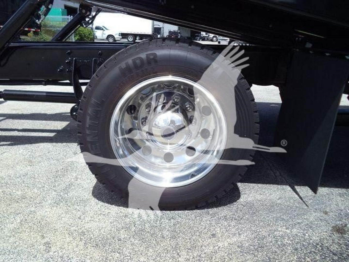 International truck wheel and tire mounted on a rollback chassis with chrome rim and black undercarriage components.