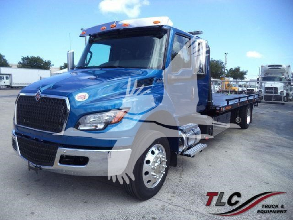 Truck showing John Deere? No, International MV rollback tow truck with blue and white cab and flatbed.