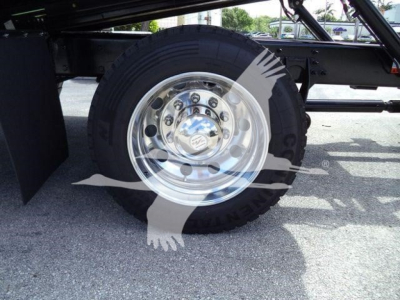 Wheel and tire of a truck undercarriage showing a chrome polished wheel with lug nut pattern and heavy-duty tire on black chassis.