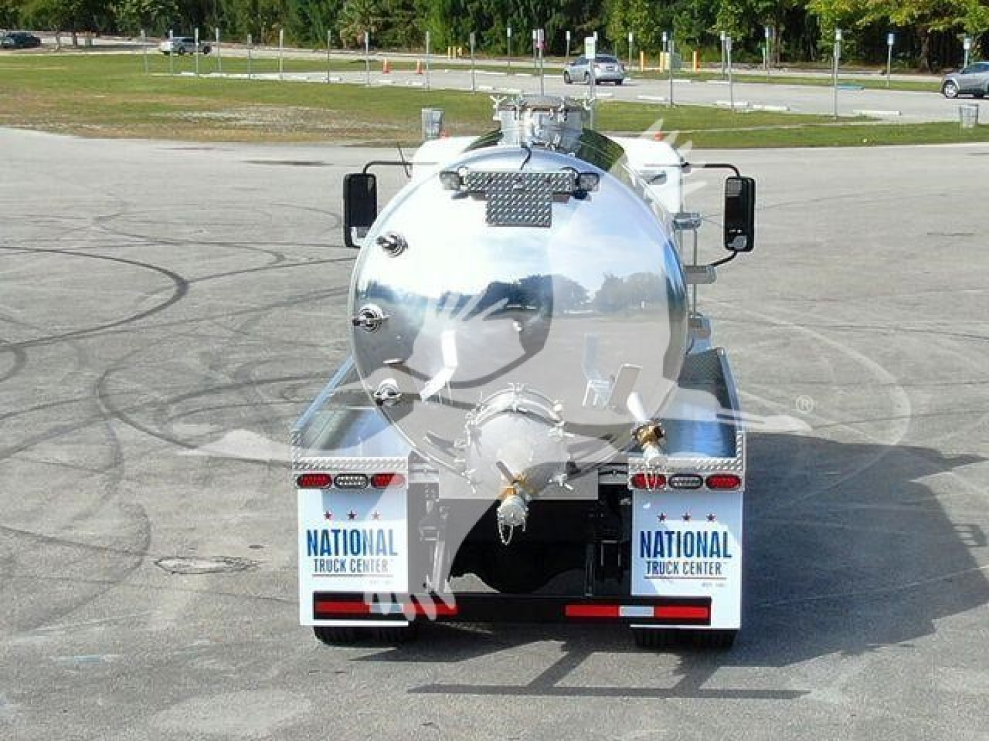 Sewer service tanker truck back view showing cylindrical stainless tank and rear bay with National Truck Center decals.
