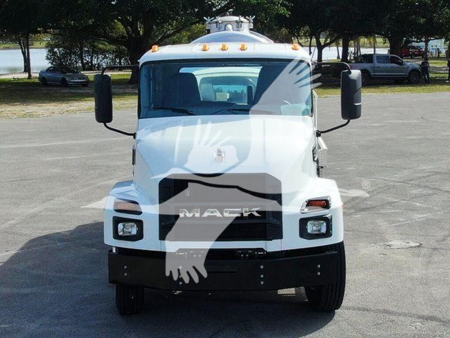 Front view of a white Mack MD7 truck with black grille and bumper, large side mirrors, orange marker lights on cab roof. The word 'MACK' on grille.