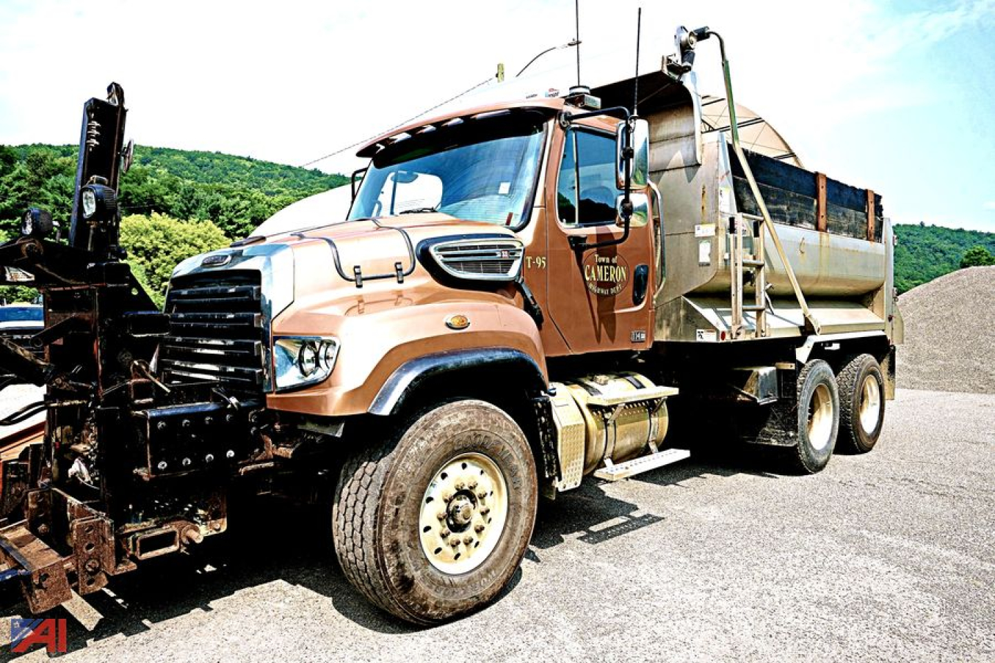 Truck side view showing 2013 Freightliner SD114 dump bed with plow attachment and front grille; cab and wheels visible.