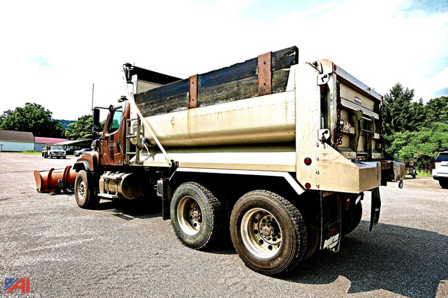 Dump truck side/rear view showing bed in raised position and plow attachment visible at front; 2013 Freightliner SD114 dump truck.