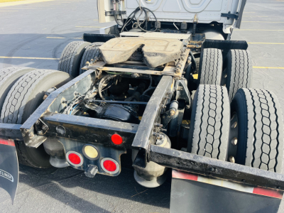 Tractor rear chassis of a Freightliner Cascadia 125 truck showing fifth-wheel, dual rear axles, and mud flaps with red and orange lights.