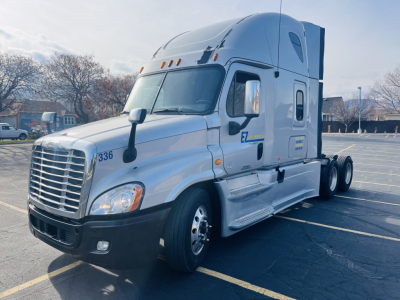 2013 Freightliner Cascadia 125 tractor-trailer cab in polished white with sleeper, front three-quarter view showing chrome grille, headlights, side mirrors, and EZ logo on door.