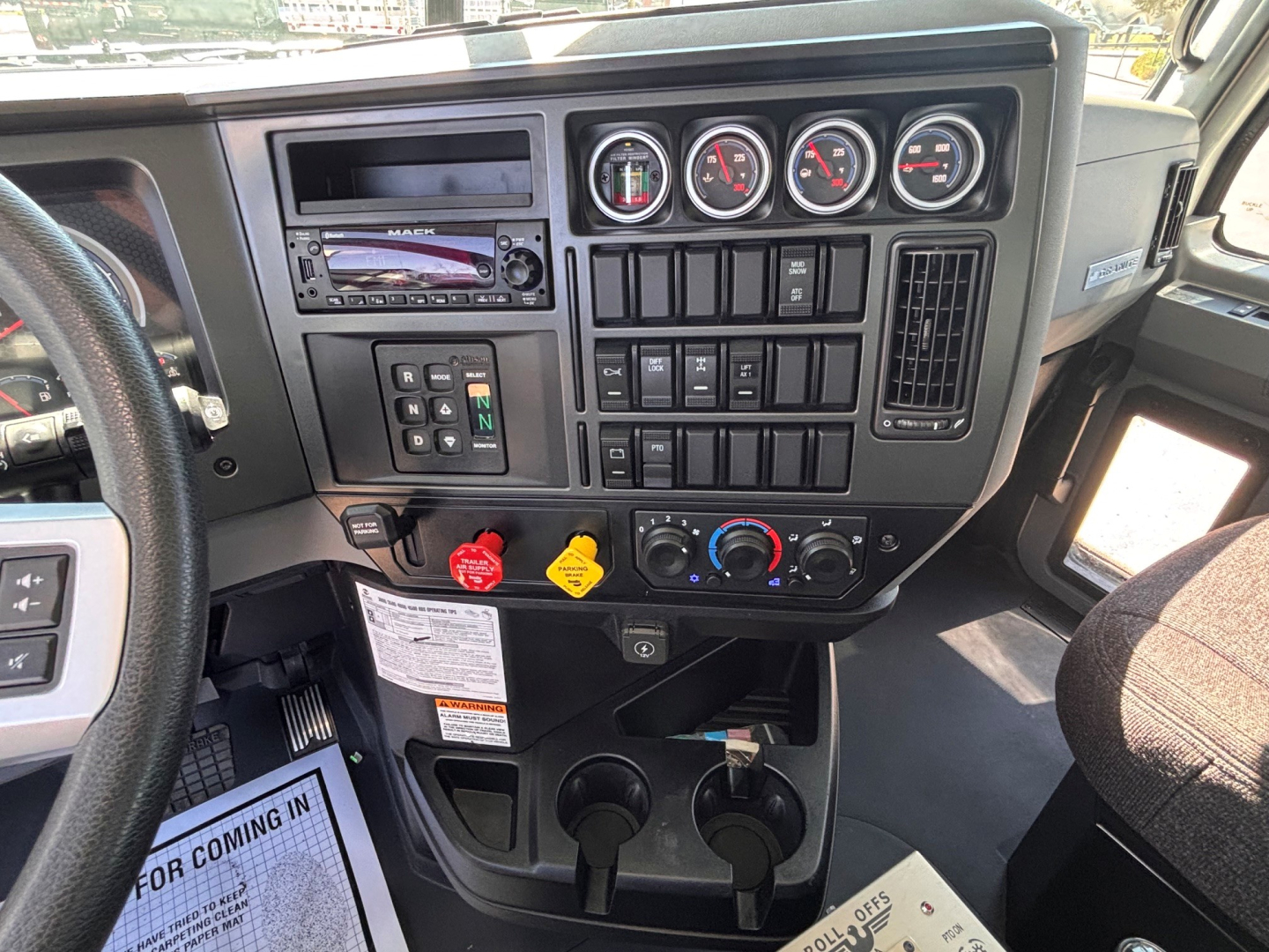 Dashboard of a 2026 Mack GR64B showing instrument cluster, radio, push buttons, climate controls, and cab accessories.