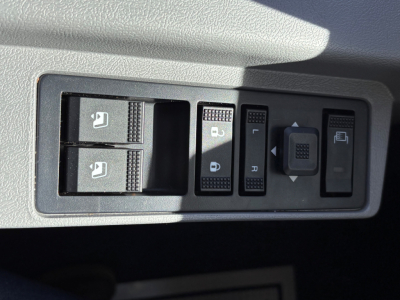 Panel view showing window/lock switches and mirror controls inside a Mack GR64B truck cab. Includes two window switches, central locking, and mirror adjustment controls.