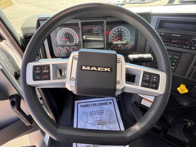 Steering wheel interior of a Mack GR64B truck showing the central Mack badge, instrument cluster, and control buttons on the dashboard.