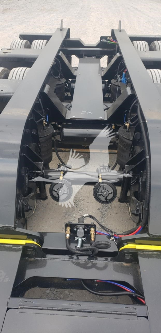 Lowboy trailer hitch area showing frame rails, hydraulic lines, and components including winches and wiring harnesses.