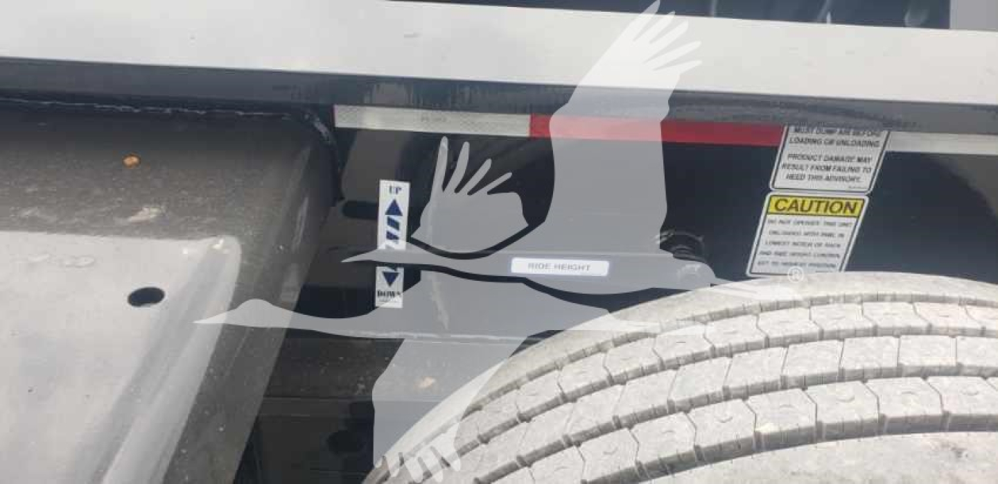 Trailer side showing warning decals and tire; text includes caution label and sticker marks.