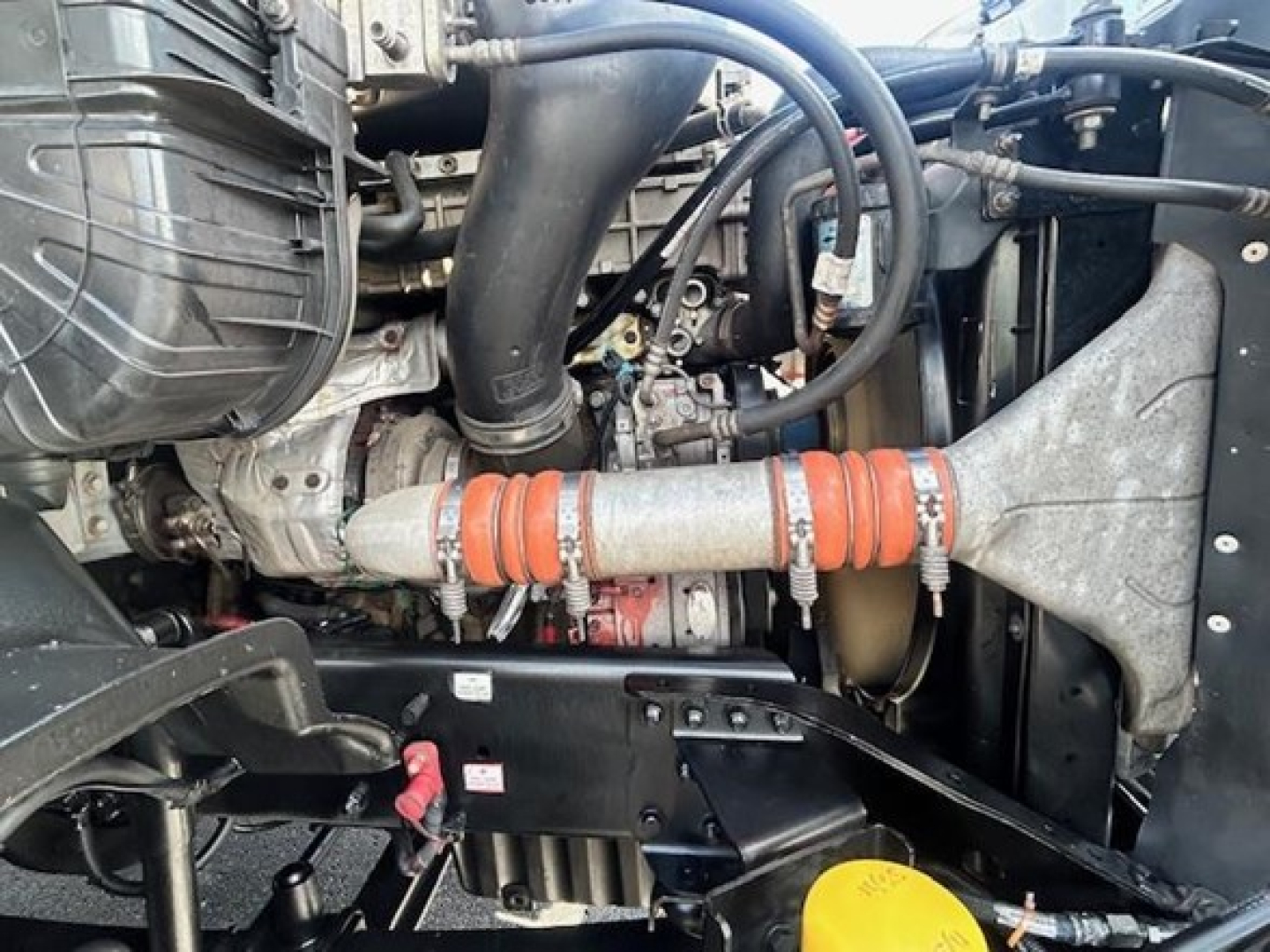 Freightliner Cascadia engine bay showing turbo intake and orange booted hoses with component labels.