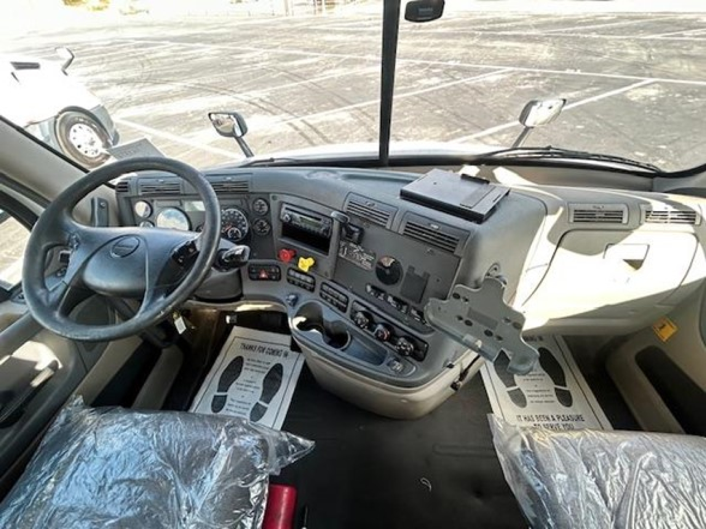 Dashboard and driver's seat area of a 2016 Freightliner Cascadia 113 Evolution tractor cab interior.
