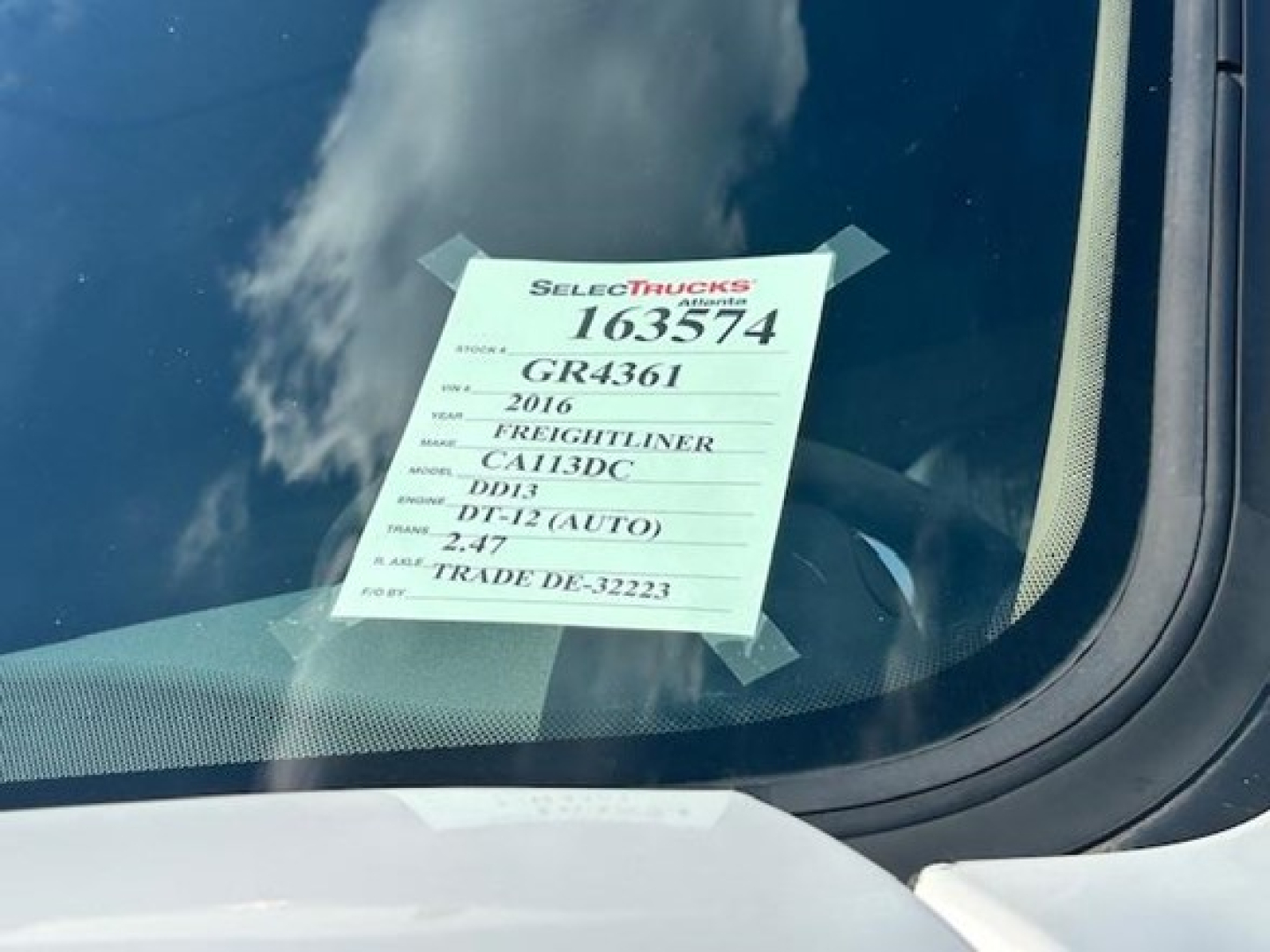 Equipment tag on Freightliner Cascadia windshield showing stock number 163574, GR4361, model year 2016, DT12 (Auto) transmission, DD13 engine, 2.17 axle ratio.
